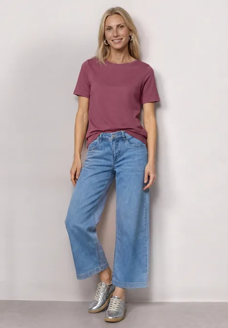 Basic Shirt met ronde hals in Unifarbe dark clouded blush Vrouw voor neutrale achtergrond in roze t-shirt, wijd blauwe jeans en zilverkleurige sneakers.