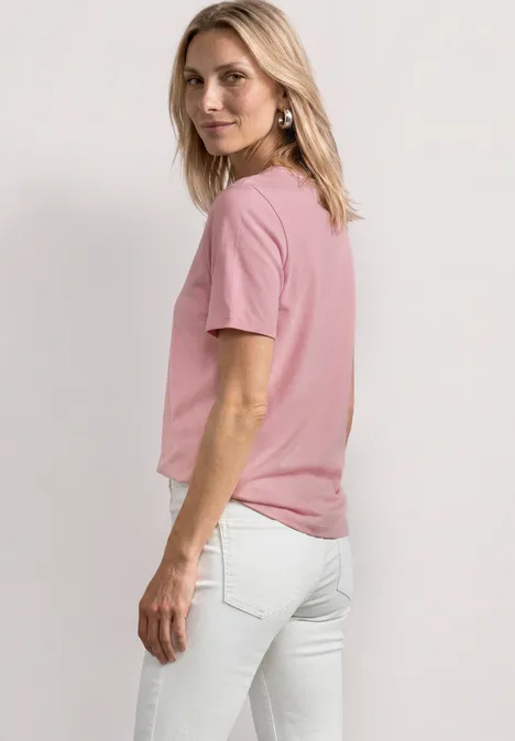 Basic T-Shirt mit Rundhals in Unifarbe vintage blush Seitliche Ansicht einer Frau in rosa T-Shirt und weißen Jeans vor hellem Hintergrund.