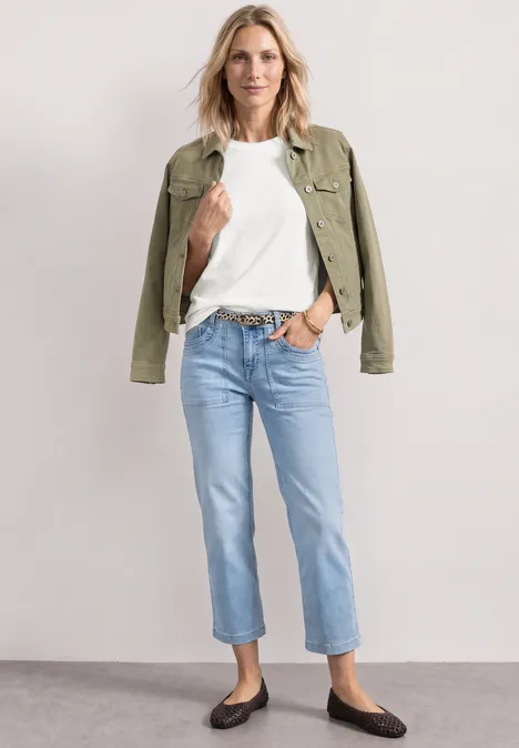 Basic T-Shirt mit Rundhals in Unifarbe off white Frau in weißem T-Shirt, Jeans, grüner Jacke und flachen schwarzen Schuhen.