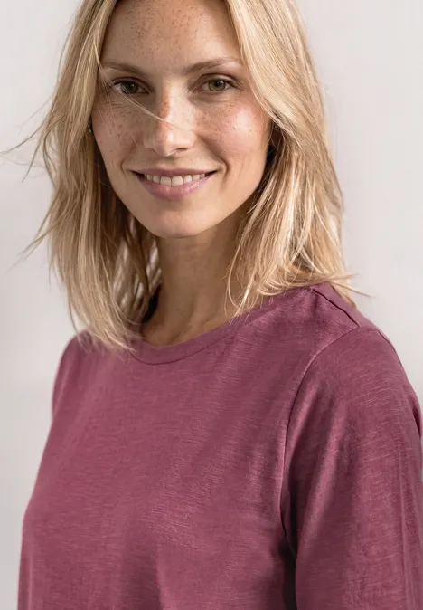 Basic T-Shirt mit Rundhals in Unifarbe dark clouded blush Person mit verpixeltem Gesicht und hellblonden, schulterlangen Haaren trägt ein langärmeliges, pinkes Shirt.