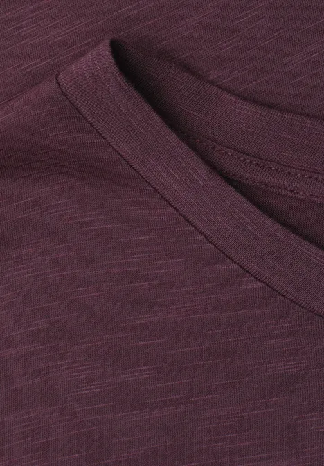 Nahaufnahme eines burgunderfarbenen T-Shirts mit Rundhalsausschnitt und feinen Stoffstrukturen.