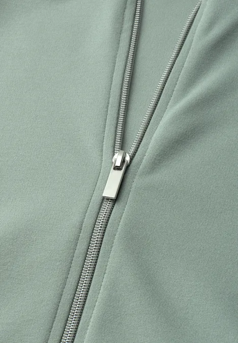 Jas met lange mouwen en een korter model eucalyptus green Close-up van een saliegroen kledingstuk met een zilverkleurige rits.