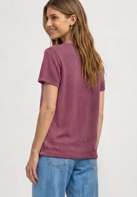 Vrouw van achteren in een paars t-shirt en blauwe jeans, casual outfit.