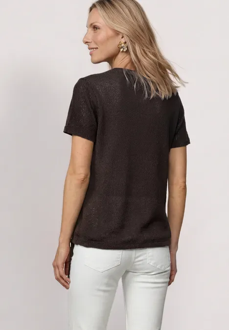 Vrouw van achteren in zwart t-shirt en witte broek, halflang blond haar.