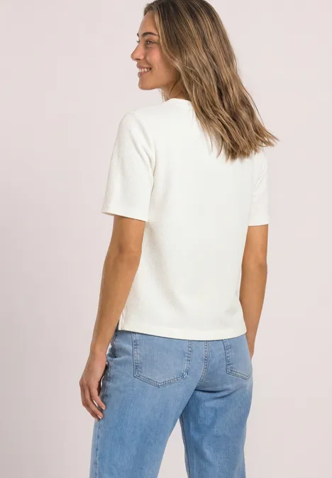 T-Shirt mit Rundhals und Struktur off white Frau von hinten in weißem Kurzarmshirt und Jeans, sie lächelt und blickt seitlich, mittelblonde Haare.
