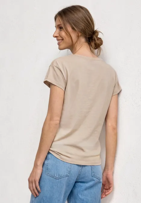 T-Shirt mit Rundhals und Foliendetails clay sand Frau mit Hochsteckfrisur, beige T-Shirt und blauen Jeans, Rückenansicht vor hellem Hintergrund.