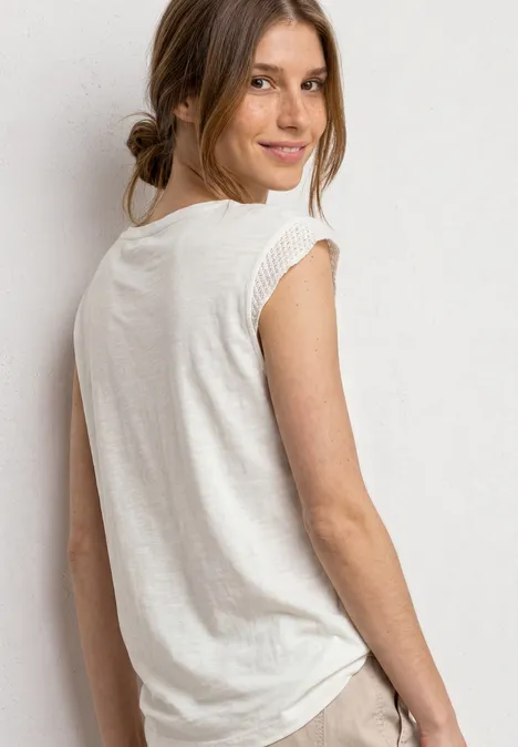 Een vrouw in een wit T-shirt kijkt over haar schouder en lacht.