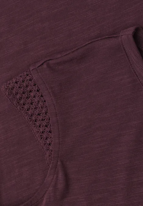 Close-up van paarsachtig shirt met zakje en verfijnde gehaakte rand.