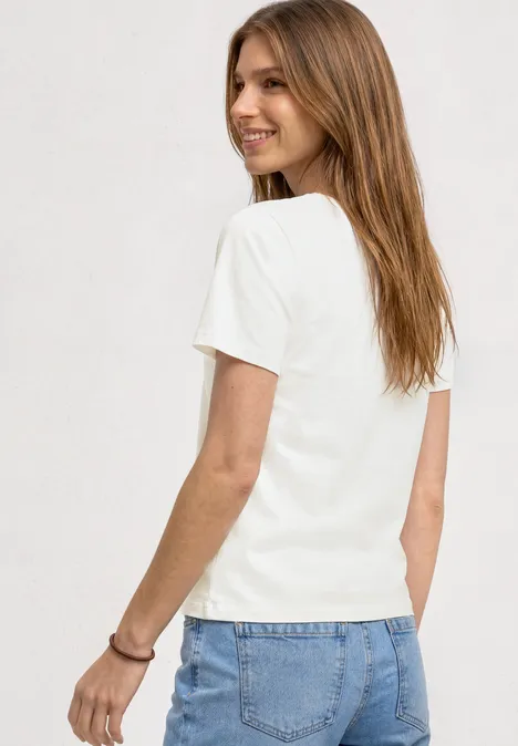 Eine Frau von hinten in weißem T-Shirt und blauer Jeans.