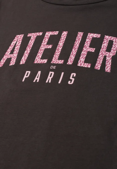 T-shirt noir avec inscription rose 'ATELIER de PARIS'.