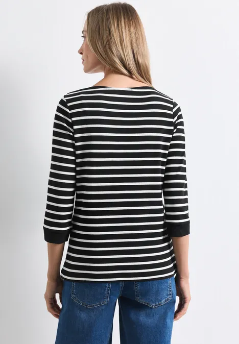 Frau von hinten in schwarzem, weiß geringeltem 3/4-Arm-Shirt und blauen Jeans.