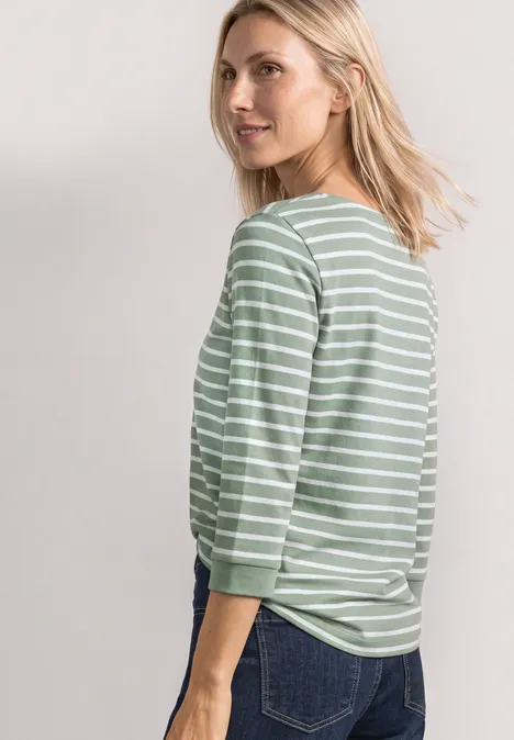 T-shirt à manches 3/4 et col bateau eucalyptus green Eine Frau im grünen, weiß gestreiften Langarmshirt blickt über die Schulter.