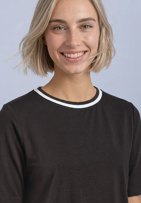Uśmiechnięta blondynka w czarnej koszulce na jasnym tle.