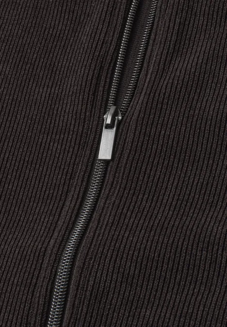 Close-up van een zwarte metalen rits op donker ribfluweel.