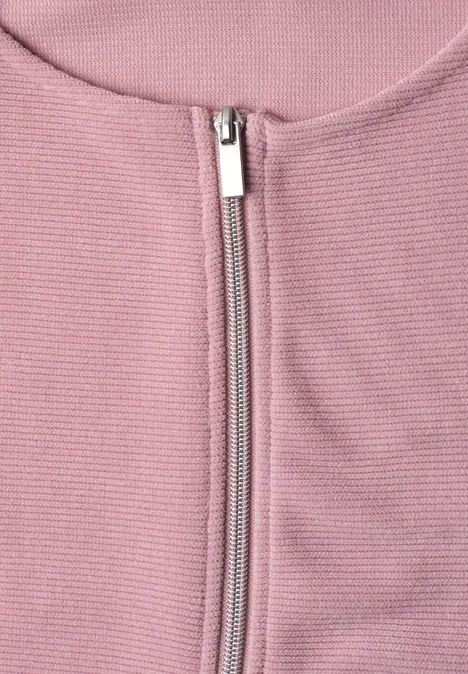 Nahaufnahme eines rosa Rippstrick-Oberteils mit silbernem Reißverschluss und rundem Ausschnitt.