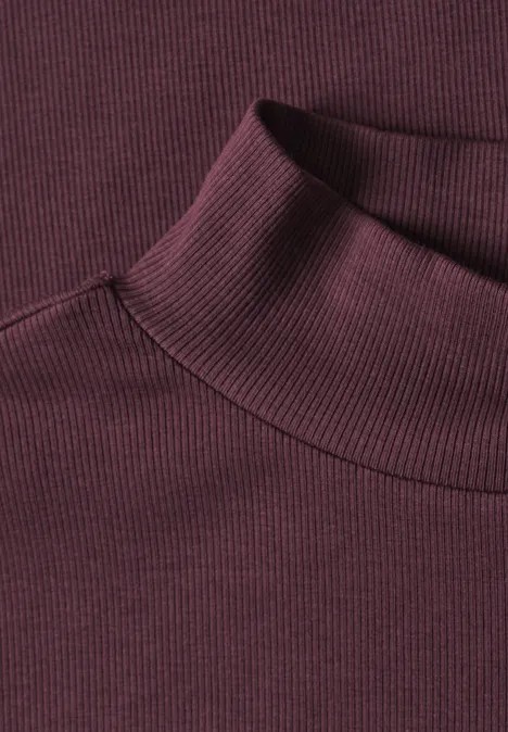 T-shirt à col roulé en maille côtelée rustic rouge Detailaufnahme eines burgunderroten, fein gerippten Rollkragen-Pullovers.