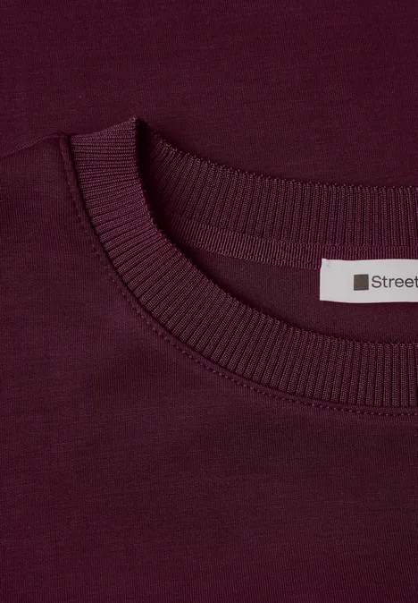 T-shirt à col rond avec un aspect soyeux rustic rouge Gros plan sur un t-shirt bordeaux à col rond avec étiquette 'Street'.