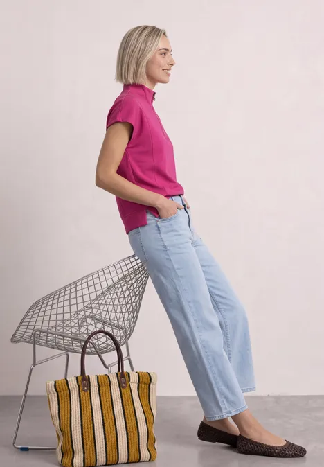 Ärmelloses Shirt im Silk-Look mit Zipper magenta dream Frau in pinkem Shirt sitzt auf Drahtstuhl, trägt weite Jeans und flache Schuhe, neben ihr steht eine gestreifte Tasche.