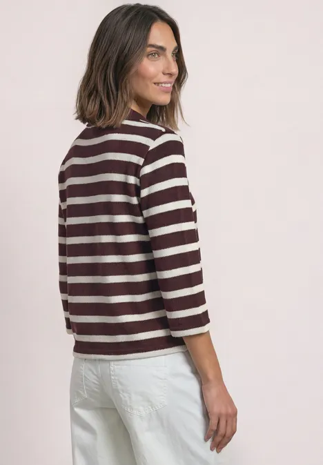 3/4-Arm Poloshirt mit Streifenmuster rustic rouge Frau in weißer Hose und bordeaux-weiß gestreiftem Shirt blickt lächelnd über die Schulter.
