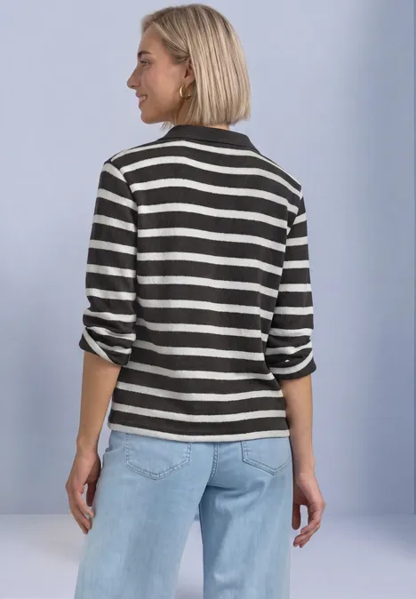 3/4-Arm Poloshirt mit Streifenmuster black coffee Frau von hinten in schwarz-weiß gestreiftem Shirt und hellblauen Jeans vor hellem Hintergrund.