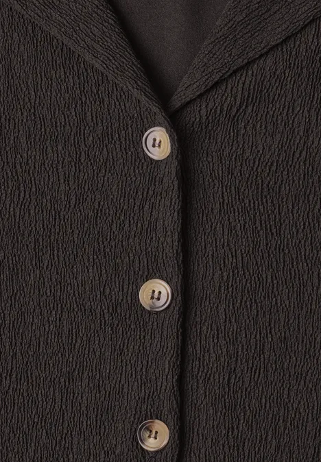 Vorderseite eines schwarzen, strukturierten Blazers mit drei cremefarbenen Knöpfen.