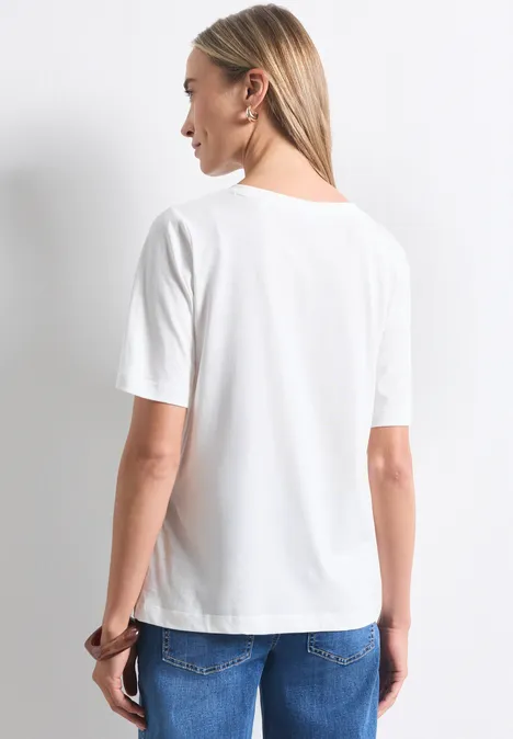 T-shirt à col rond avec impression photo off white Eine Frau steht mit dem Rücken zur Kamera, trägt ein weißes T-Shirt und blaue Jeans.