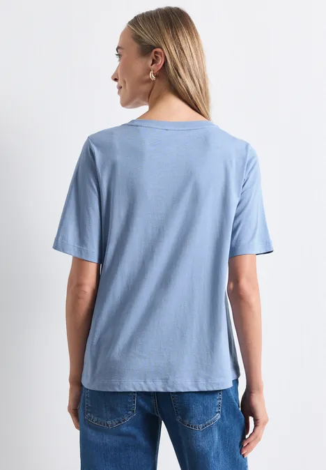 T-shirt à col rond avec impression photo northern blue Eine Frau steht mit dem Rücken zur Kamera, sie trägt ein hellblaues T-Shirt und Jeans.