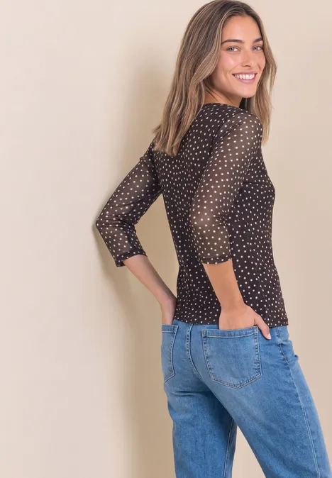 3/4-Arm Shirt aus Mesh mit Print black coffee Junge Frau im Profil trägt schwarzen Pullover mit weißen Punkten und blaue Jeans, lächelt über die Schulter.