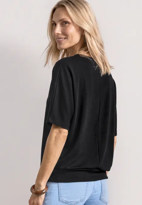 Basic Shirt met boothals en elastische zoom Black Vrouw van achteren in een zwart t-shirt en een blauwe spijkerbroek.