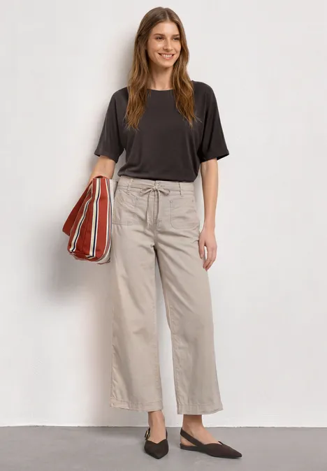 Basic Shirt met boothals en elastische zoom black coffee Vrouw in zwart T-shirt, beige wijde broek, zwarte ballerina’s en rood gestreepte shopper.