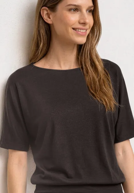 Basic Shirt met boothals en elastische zoom black coffee Vrouw met halflang bruin haar draagt een eenvoudig zwart t-shirt tegen een lichte achtergrond.