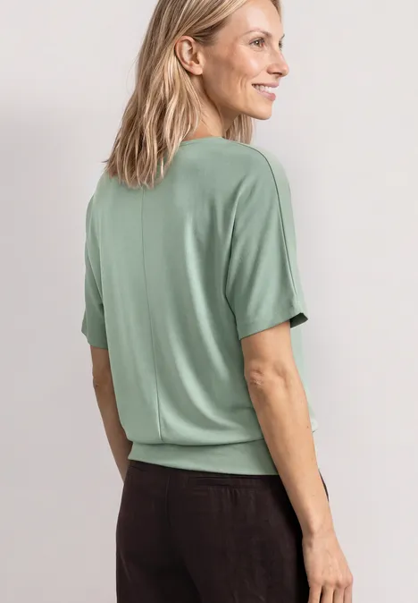 Basic Shirt met boothals en elastische zoom eucalyptus green Achteraanzicht van een persoon in mintgroene korte mouw top en donkere broek tegen lichte achtergrond.