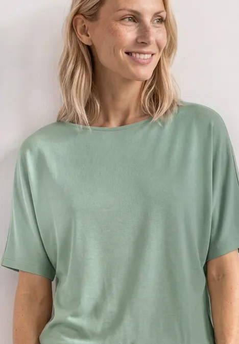 Basic Shirt met boothals en elastische zoom eucalyptus green Vrouw in lichtgroene top, glimlachend met halflang blond haar.
