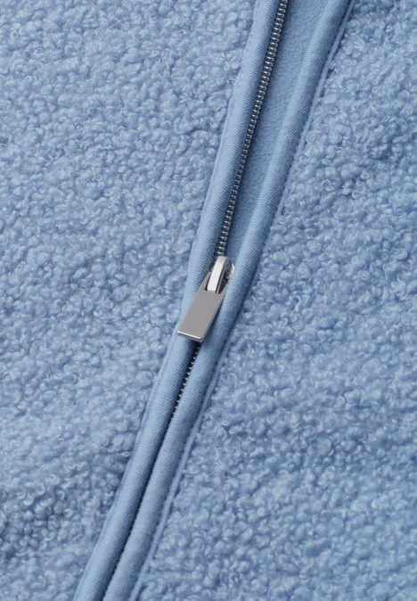 Nahaufnahme eines hellblauen Sherpa-Fleecestoffes mit Reißverschluss.