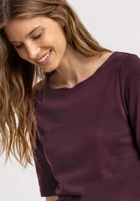 Frau mit lockigen Haaren trägt einen dunkelroten Pullover, Blick seitlich, Gesicht unscharf