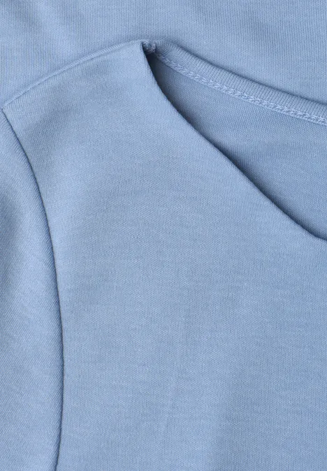 T-shirt à encolure ondulée, couleur unie northern blue Nahaufnahme einer hellblauen Kapuzenpullover-Tasche mit sichtbaren Nähten.