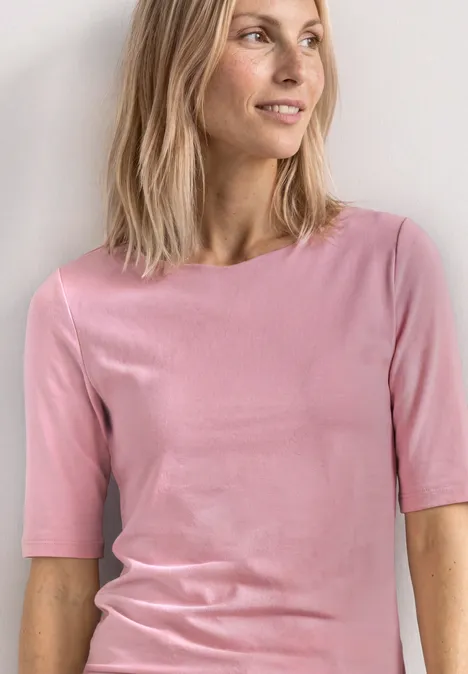 Shirt met golvende halslijn in effen kleur vintage blush Persoon draagt een strakke roze t-shirt en halflang haar tegen een lichte achtergrond.