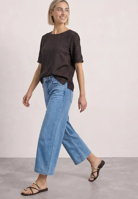 Frau mit schwarzem T-Shirt und weitem Jeans läuft lächelnd.