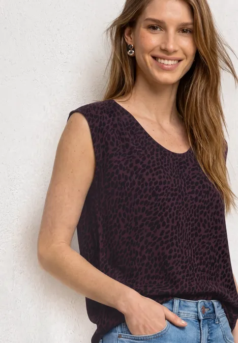 Shirt mit Boat Neck und Elastikbund rustic rouge Frau im ärmellosen, dunkelroten Leoparden-Top und Jeans vor weißer Wand.
