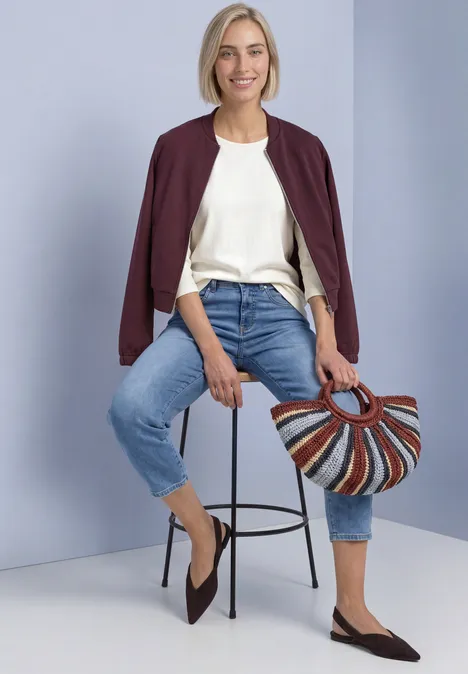 3/4-Arm Shirt mit U-Boot-Ausschnitt off white Frau in weißem Shirt, Jeans und burgunderrotem Jäckchen sitzt auf einem Hocker und hält eine bunte Korbtasche.