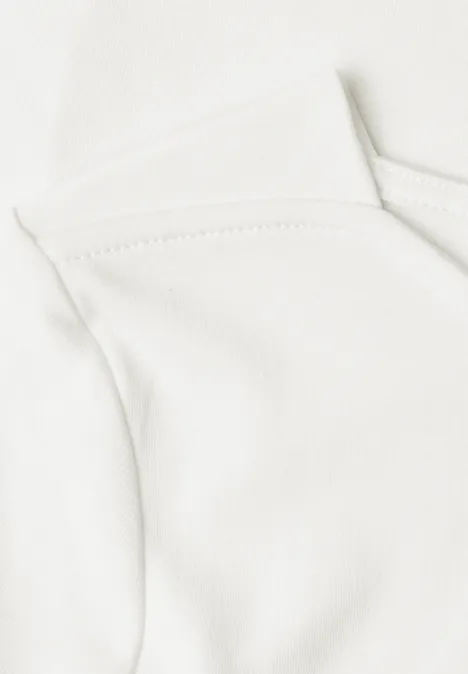 Nahaufnahme eines weißen Baumwollshirts, das den oberen Ausschnitt und die Schulterpartie zeigt.