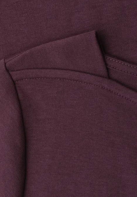 Detailaufnahme eines weinroten Baumwoll-T-Shirts mit Rundhalsausschnitt und feiner Naht.