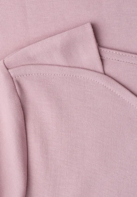 3/4-Arm Shirt mit U-Boot-Ausschnitt quiet rose Nahaufnahme von rosa Baumwollstoff mit sichtbaren Nähten, vermutlich Teil eines T-Shirts oder Babykleidung.