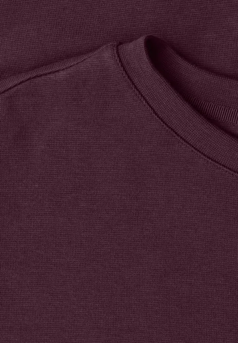 Zbliżenie na bordowy kołnierz bluzy z miękkiego materiału.