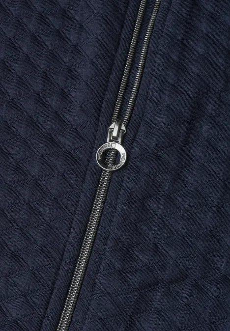 Gestepptes, dunkelblaues Textil mit mittig platziertem Reißverschluss und rundem Zipper-Anhänger.