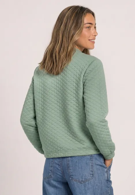 Frau von hinten mit grüner gesteppter Jacke und blauen Jeans.