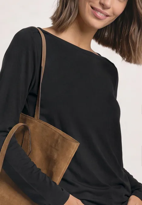 Basic Shirt mit U-Boot-Ausschnitt Black Frau in schwarzem Langarmshirt mit brauner Wildleder-Umhängetasche über der Schulter.