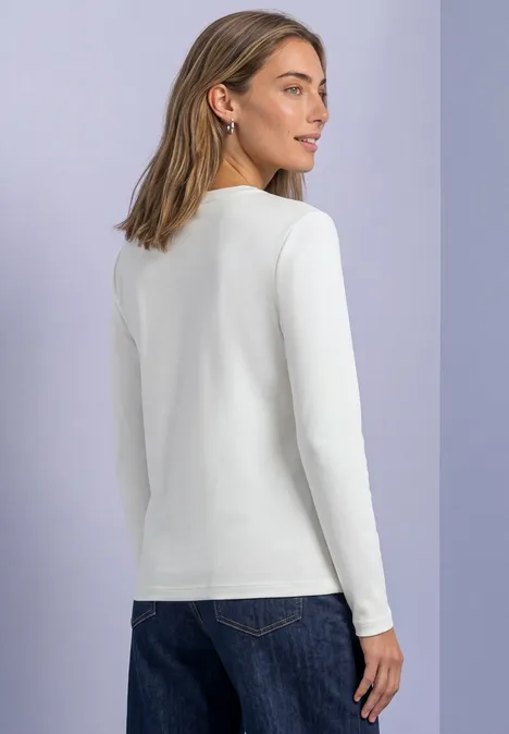 Basic Shirt mit U-Boot-Ausschnitt off white Frau mit weißem Langarmshirt und Jeans, von hinten, vor pastellfarbenem Hintergrund.