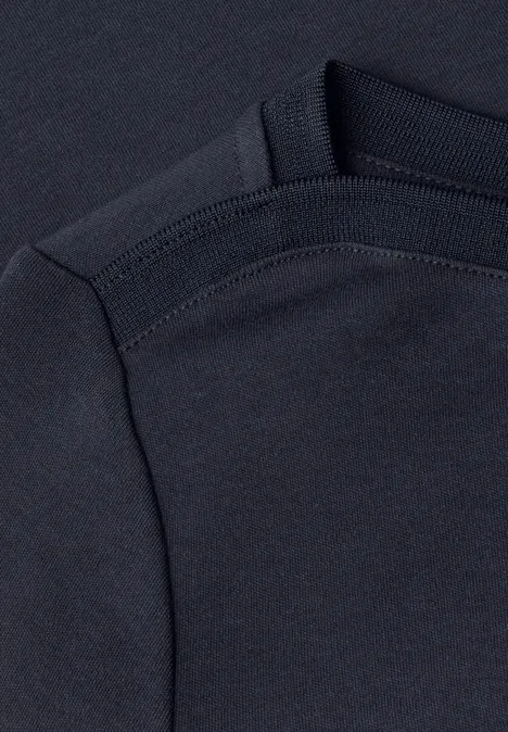Gros plan d'un t-shirt bleu foncé montrant la couture de l'épaule et de la manche.