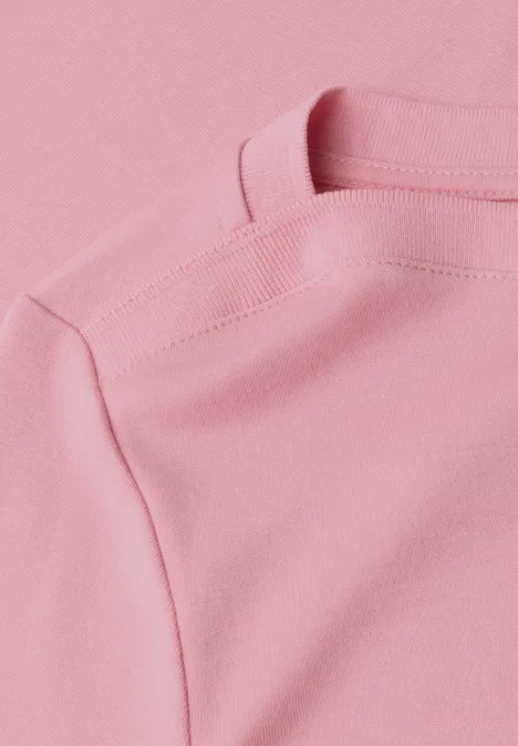 Nahaufnahme eines pastellrosa T-Shirts mit sichtbarer Schulternaht.